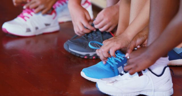 Girls tying shoe laces in basketball court at school gym