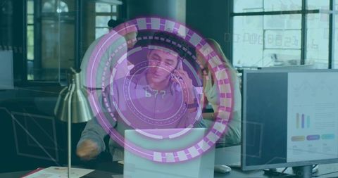 Man holding phone and consulting laptop with purple AR HUD overlay in modern office