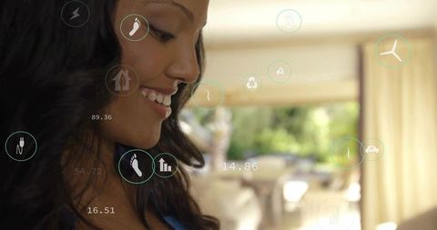 Smiling woman using augmented reality smart home interface displaying energy metrics