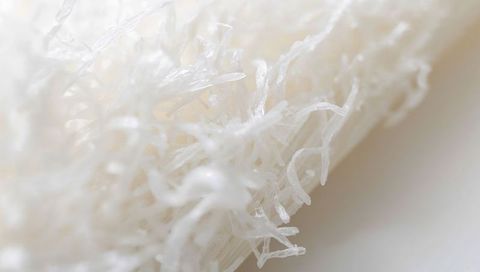 Macro translucent white fibers forming tangled delicate filaments and soft ivory texture