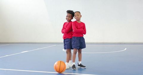 Diverse boys bonding on basketball court in red uniforms