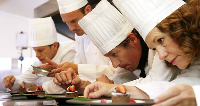 Professional chefs are intensely focused on artfully plating gourmet desserts in a professional kitchen. Ideal for content related to culinary arts, chef training programs, fine dining restaurants, and teamwork in professional kitchens.