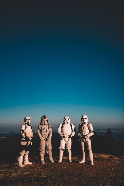 People dressed in space and Stormtrooper costumes standing together in an open outdoor location with a clear blue sky in the background. This image can be used to illustrate themes of teamwork, sci-fi and fantasy cosplay events, outdoor adventure gatherings, or themed photography projects.