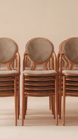 Vertical video showing stacked timber chairs with cane backs and warm beige minimalism