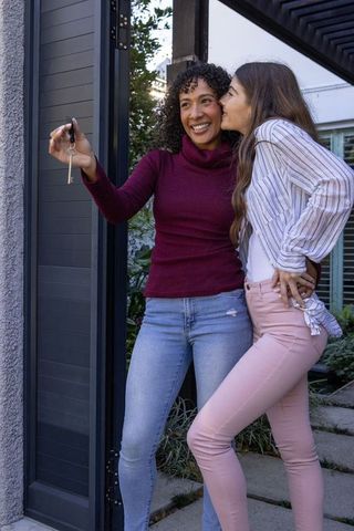 Women celebrating new home with key at modern entryway