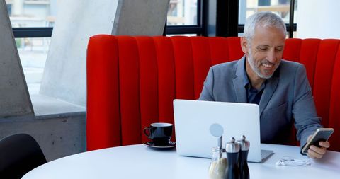 Mature Businessman Working in Modern Office with Laptop and Phone