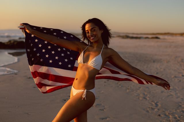 Woman in bikini holding an American flag on the beach - Download Free Stock Photos Pikwizard.com