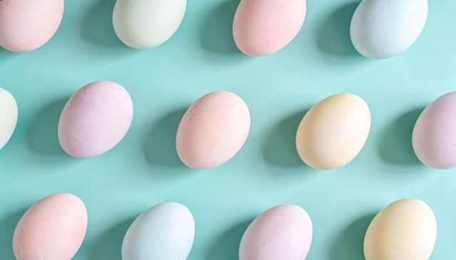 Pastel easter eggs forming staggered grid on mint background minimal spring flatlay