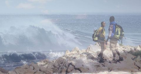 Couple Holding Hands on Rocky Coastal Trails with Backpacks