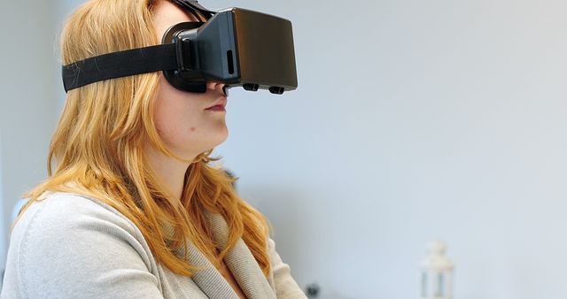 Woman using virtual reality headset while working on laptop at home