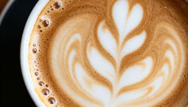 Macro latte art rosette with creamy microfoam, espresso crema and bubble rim