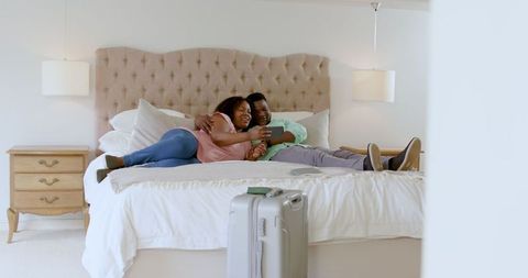 Happy Couple Relaxing on Bed with Tablet During Vacation