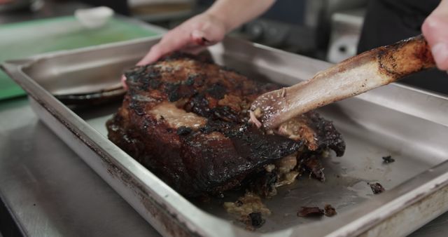 Chef slicing generously grilled beef brisket with knife in kitchen. Perfect for content on culinary skills, demonstration videos for meat preparation, barbecue recipes, food photography portfolio and professional cooking tutorials.