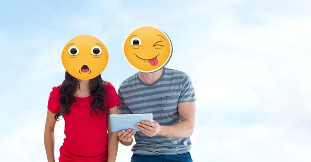 Couple with emoji faces express surprise and playfulness while using tablet outdoors under blue sky. Great for illustrating social media usage, technology trends, emotional expressions in digital contexts, or fun creative projects.