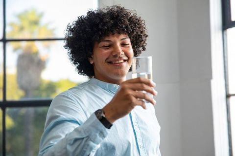 Smiling African American Man Enjoying Fresh Glass of Water in Office