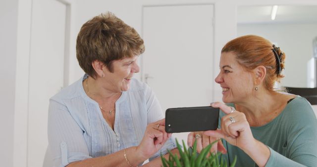 Two Mature Women Sharing a Fun Moment with Smartphone at Home - Download Free Stock Images Pikwizard.com