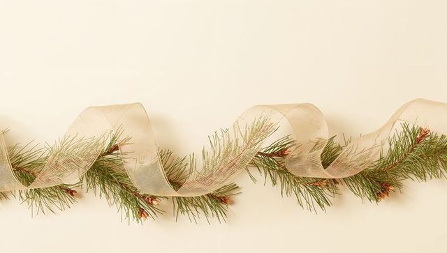Elegant pine garland with sheer gold ribbon and pinecone buds on pale cream backdrop