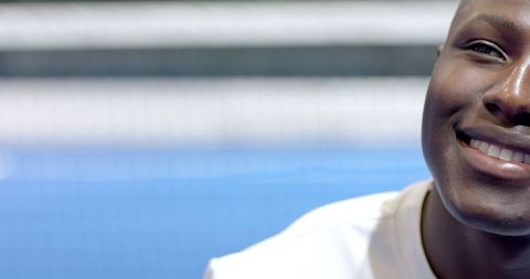 Smiling athlete on blue tennis court with net in background
