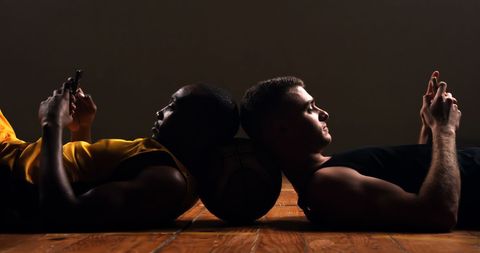 Athletes Relax on Basketball Court Using Smartphones Back-to-Back - Download Free Stock Images Pikwizard.com