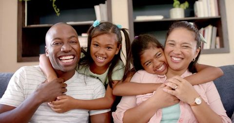 Happy Multiethnic Family Laughing at Home in Cozy Living Room