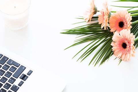 Elegant technology workspace with gerbera daisies and palm leaves