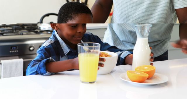 Young boy enjoying a nutritious breakfast in the kitchen, featuring cereal with milk, a glass of orange juice, and fresh oranges on a plate. This can be used for promoting healthy eating habits, family routines, and balanced diets.