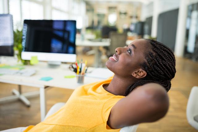 Image depicts female graphic designer in a modern office, smiling and looking relaxed. Ideal for themes related to workplace happiness, creativity, professional environments, and gender diversity in tech. Great for use in business promotions, office culture presentations, or articles on workplace wellness.