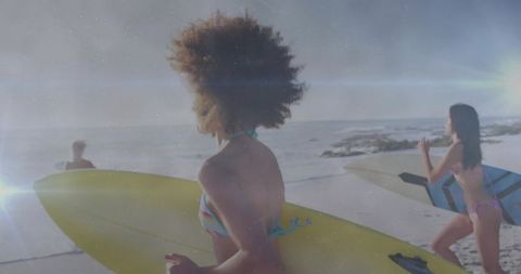 Women Walking with Surfboards along the Sandy Beach at Sunset