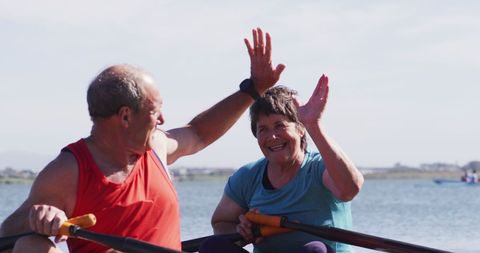 Active seniors rowing and celebrating on lake