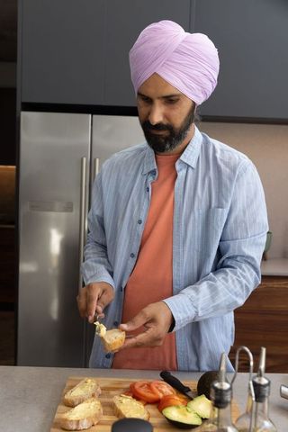 Turban-wearing man preparing toast with fresh ingredients in modern kitchen