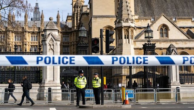 Police cordon blocking street at gothic government building, officers standing guard