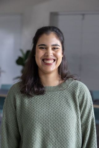 Indian woman smiling in office portrait wearing sage green sweater professional headshot
