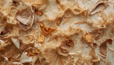 Scattering dried botanical husks and curled petals across neutral beige tabletop texture