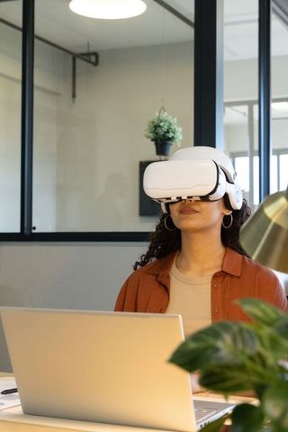 Young professional exploring virtual reality at modern office desk with laptop and plants