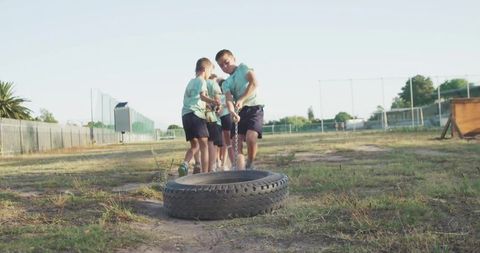 Children embracing teamwork and fitness in outdoor tire pulling activity