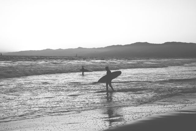 Surfers at Sunset on Tranquil Beach with Mountain Backdrop - Download Free Stock Photos Pikwizard.com