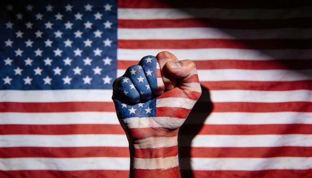 Clenching fist painted with american flag raising strength and unity over us flag backdrop
