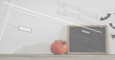 Displaying small pumpkin with plastic spider on rustic wood table with chalkboard and bats