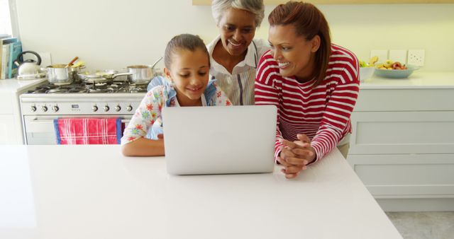 Family gathered around a laptop in a modern kitchen, showing multi-generational learning and bonding. Perfect for promoting technology usage in families, educational content, family-oriented services, and healthy home lifestyles.