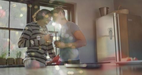 Sunlit morning romance sharing coffee by kitchen window with warm bokeh and plants
