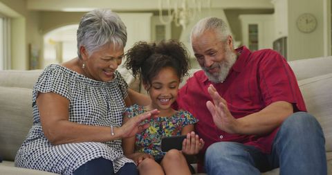 Happy Granddaughter Video Calling with Grandparents at Home