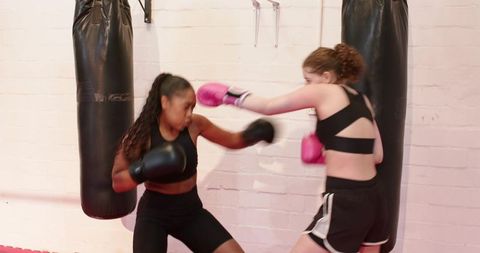 African american coach jabbing, guiding teen trainee blocking and countering in boxing gym