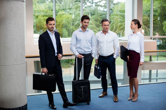 Group of business professionals standing in a modern conference center lobby and engaging in conversation. Ideal for illustrating corporate environments, business networks, or professional interactions. Can be used in business websites, corporate brochures, or articles about professional conduct and business travel.