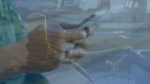 Hands of Biracial Woman Texting with Boats Overlay