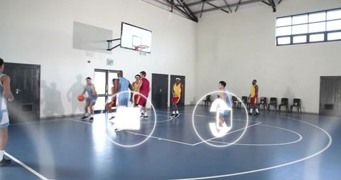 Basketball players dribbling and defending during indoor scrimmage on blue court with hoop