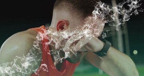 Exhausted athlete wiping face on night turf wearing smartwatch with geometric mesh overlay