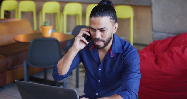 Young Man Working on Laptop While Talking on Smartphone - Download Free Stock Images Pikwizard.com