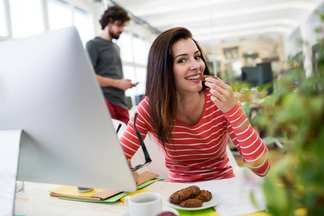 Female graphic designer having a cookie in office