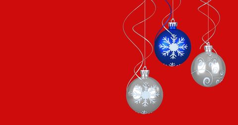 Colorful Christmas Baubles Hanging Against Red Background