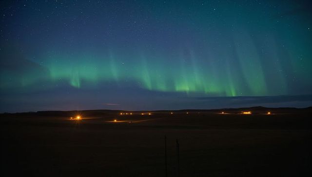 Emerald Aurora Borealis Stretching Over Remote Farmland Above Starry Night with Farm Lights